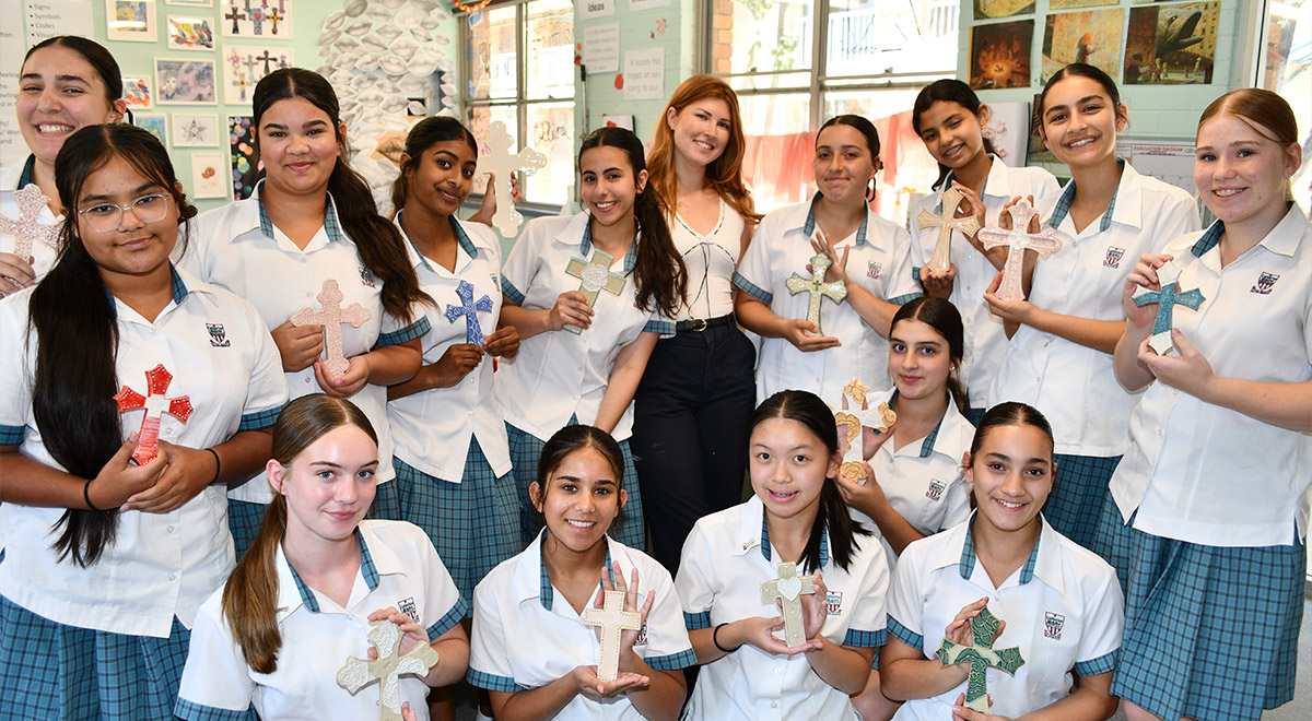 Catherine McAuley Westmead Catholic High school Visual Arts Teacher Ms Sidney Tulau with Year 8 students holding some of the ceramic crosses.